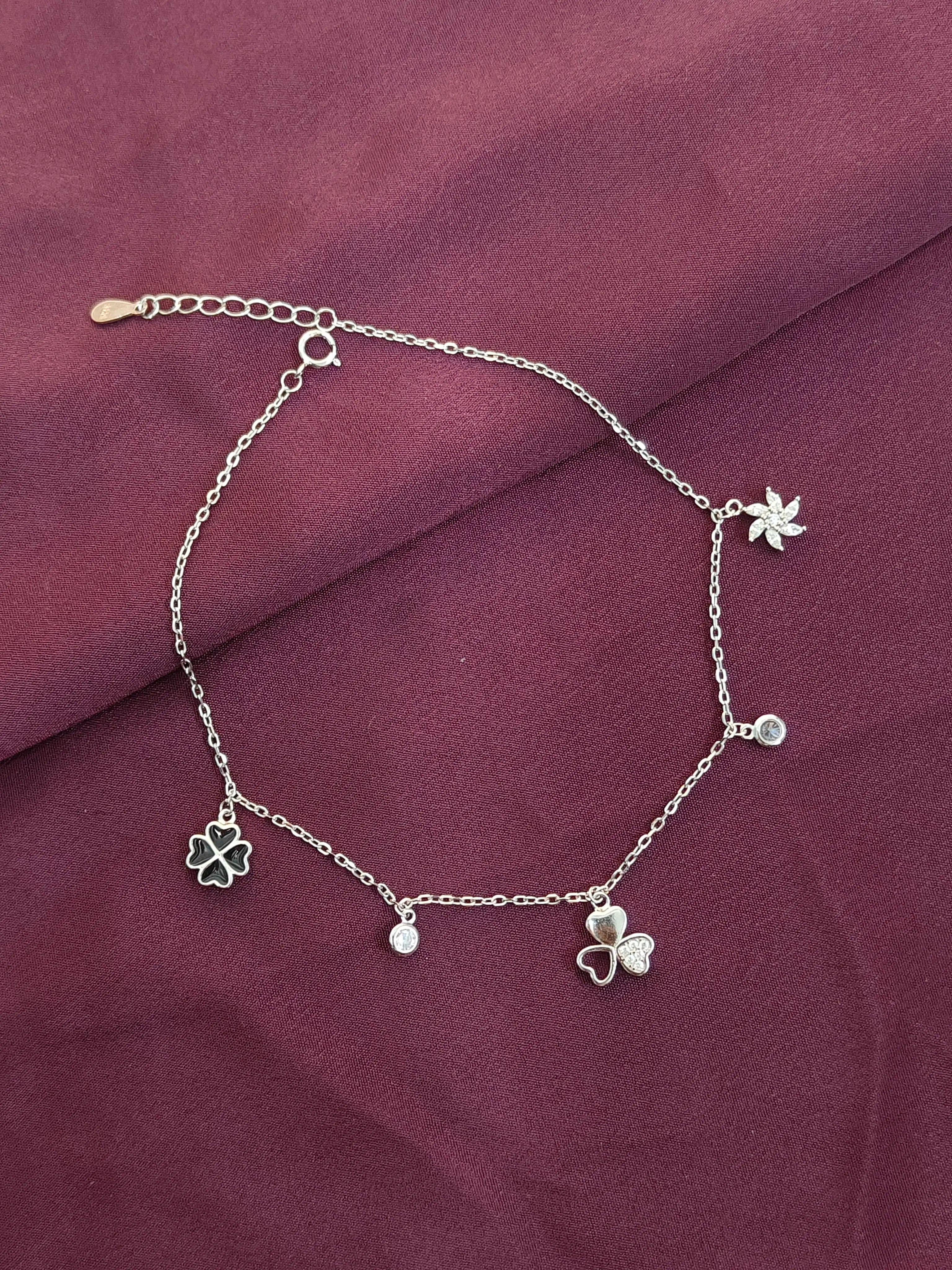 Silver bracelet with clover charms on a purple fabric background